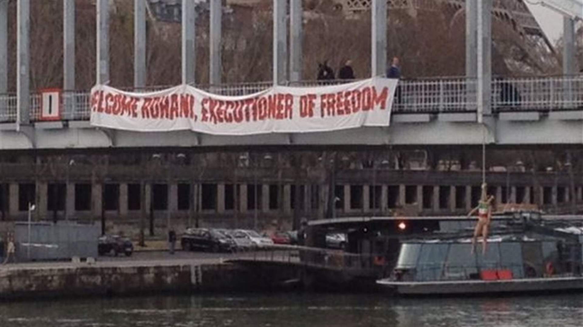 Topless Femen activist hangs from Paris bridge in anti-Rouhani protest
