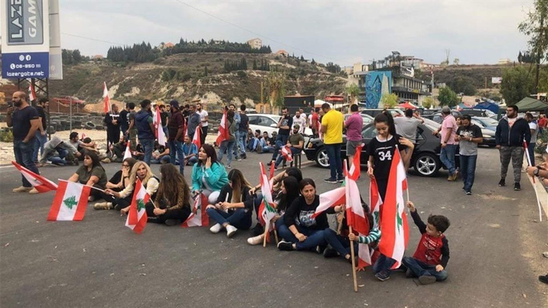 Protesters sit in the middle of the road, resisting attempts to open Kfarhazir highway